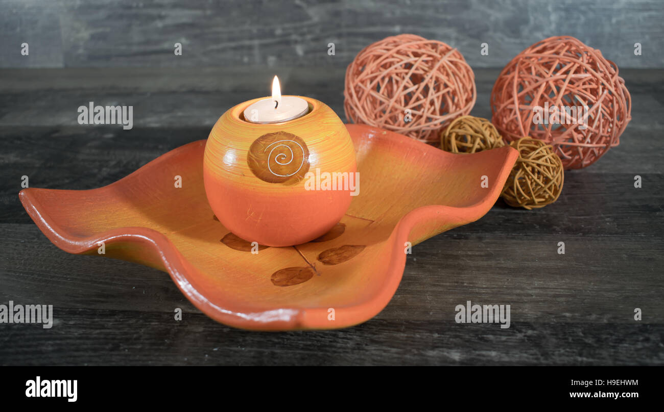 A decorative Bowl with a burning candle on a wood surface, decorated with beautiful woven balls Stock Photo