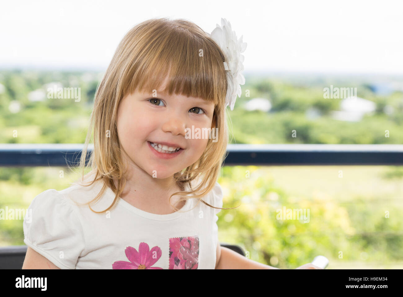 Little girl with flower in hair smiling and happy outdoors Stock Photo ...