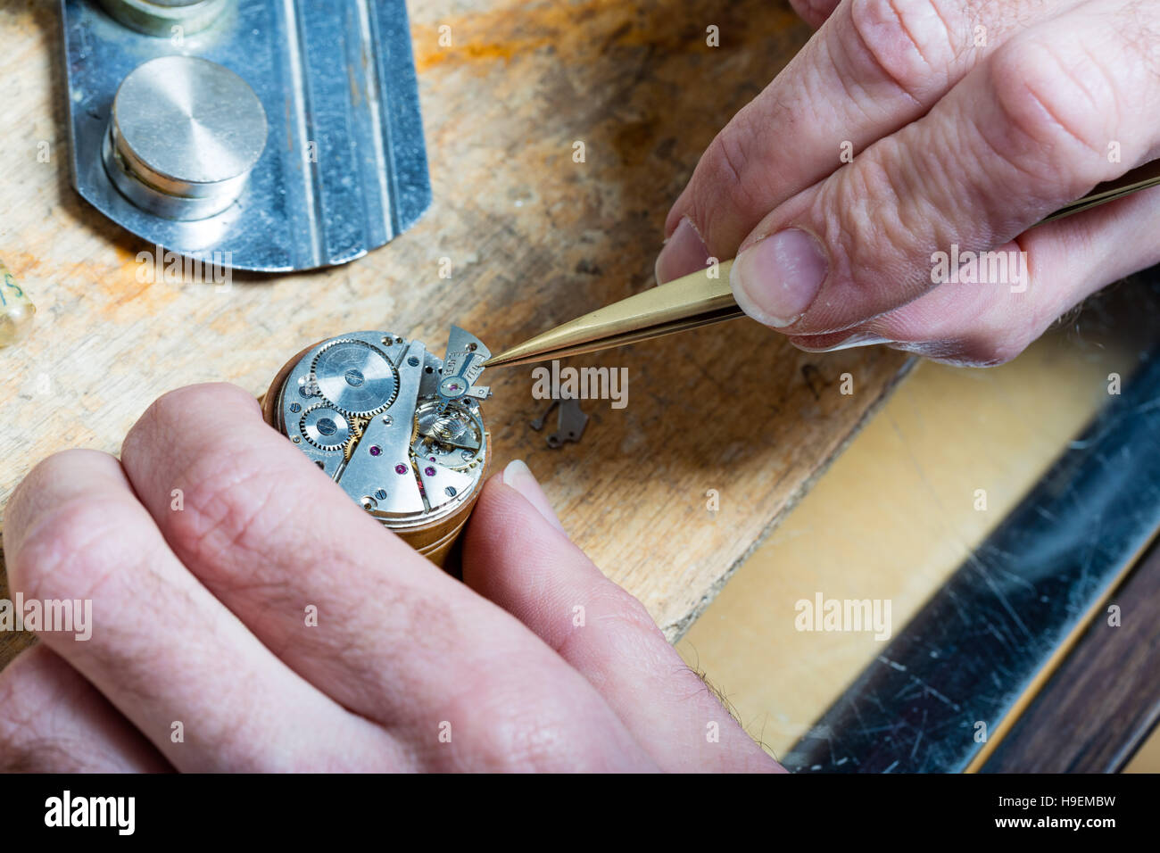 closeup of the hands of a watchmaker placing some clockworks with tweezers and fixing it Stock Photo