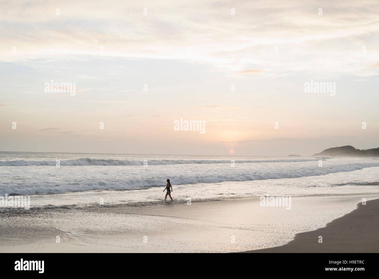 Caucasian woman walking on beach at sunset Stock Photo