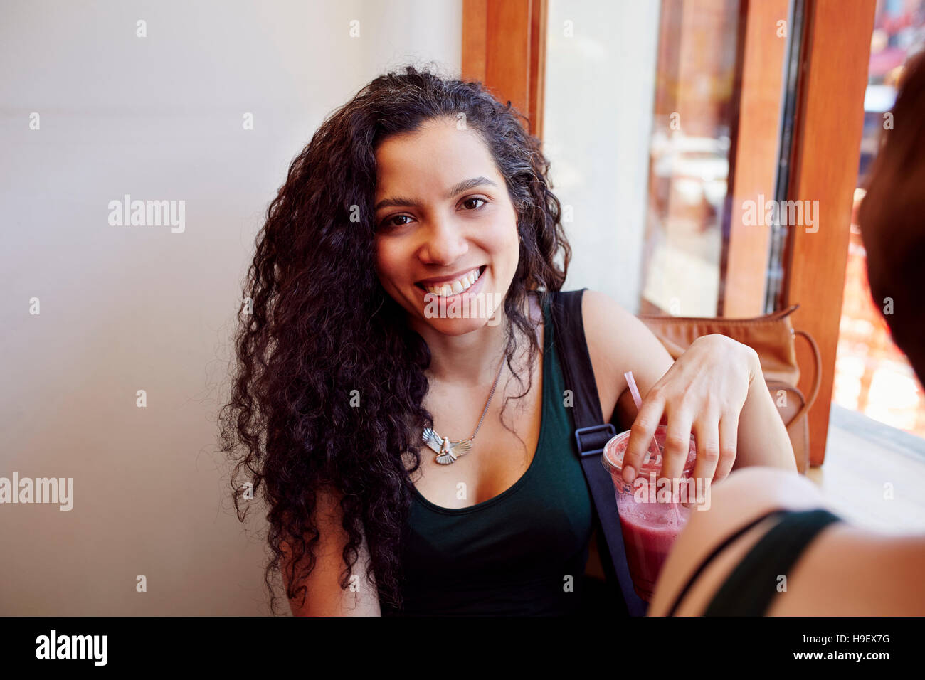 Smiling Black woman drinking smoothie in cafe Stock Photo