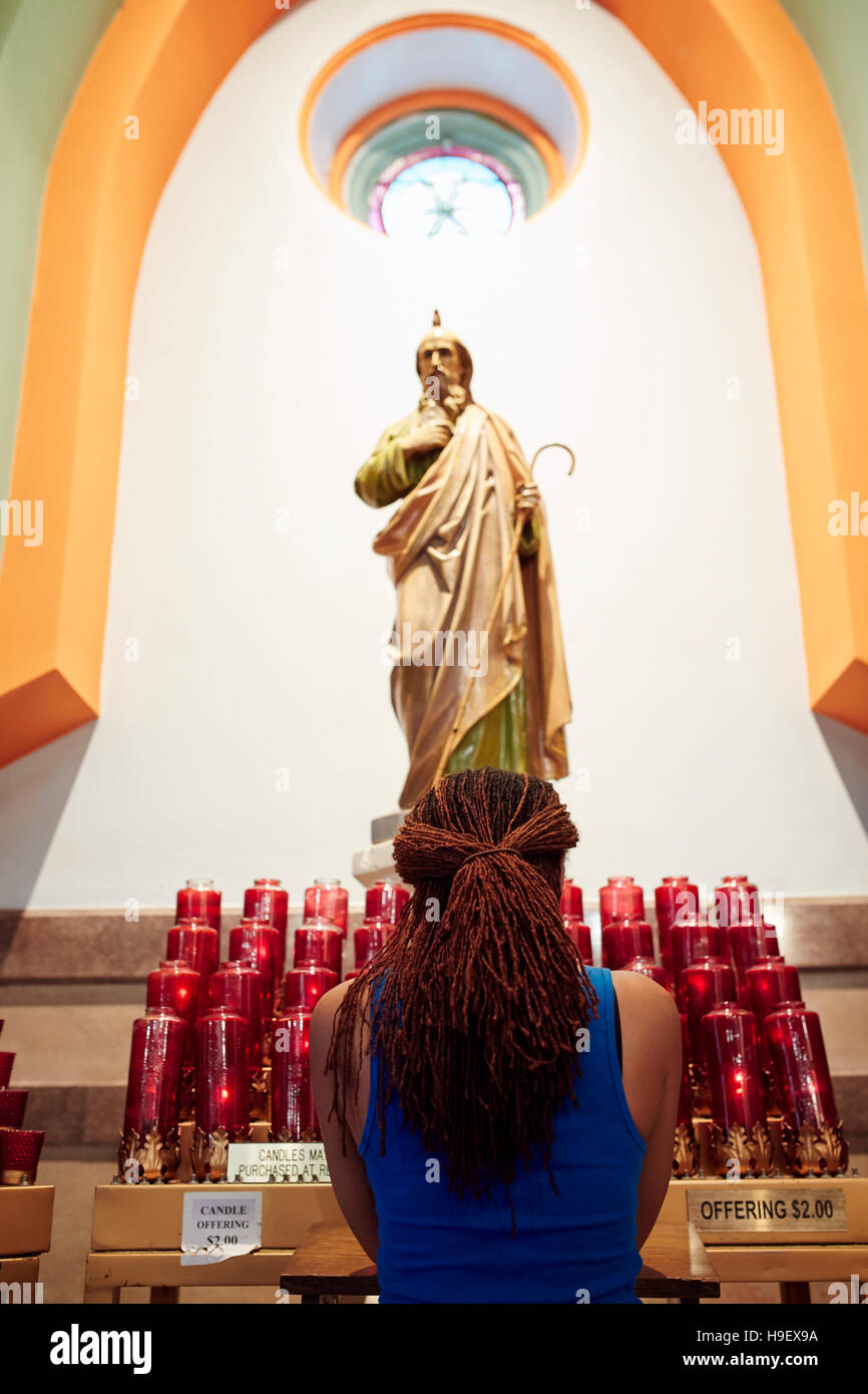 Kneeling woman praying to statue in church Stock Photo
