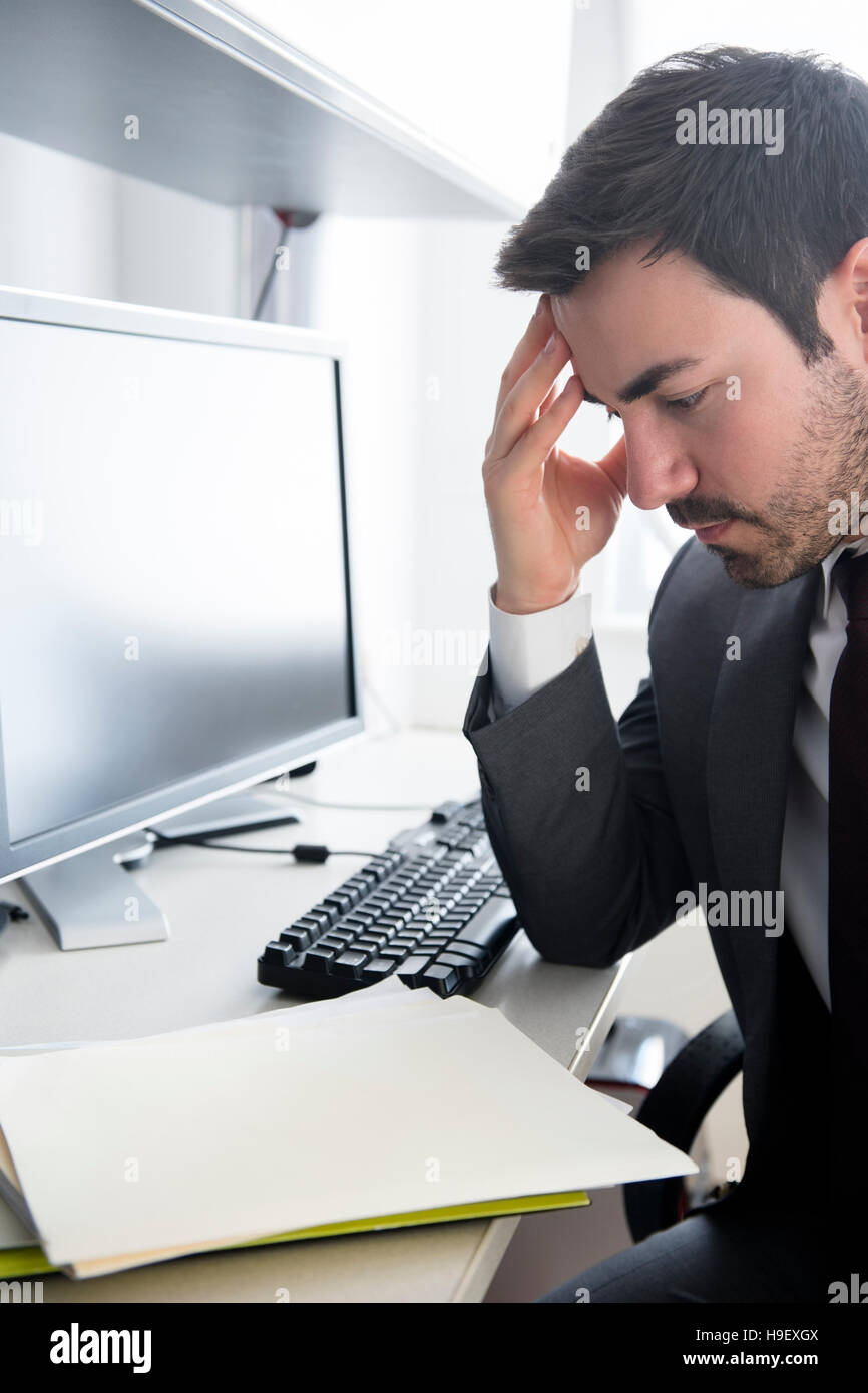 Businessman with headache at office desk Stock Photo