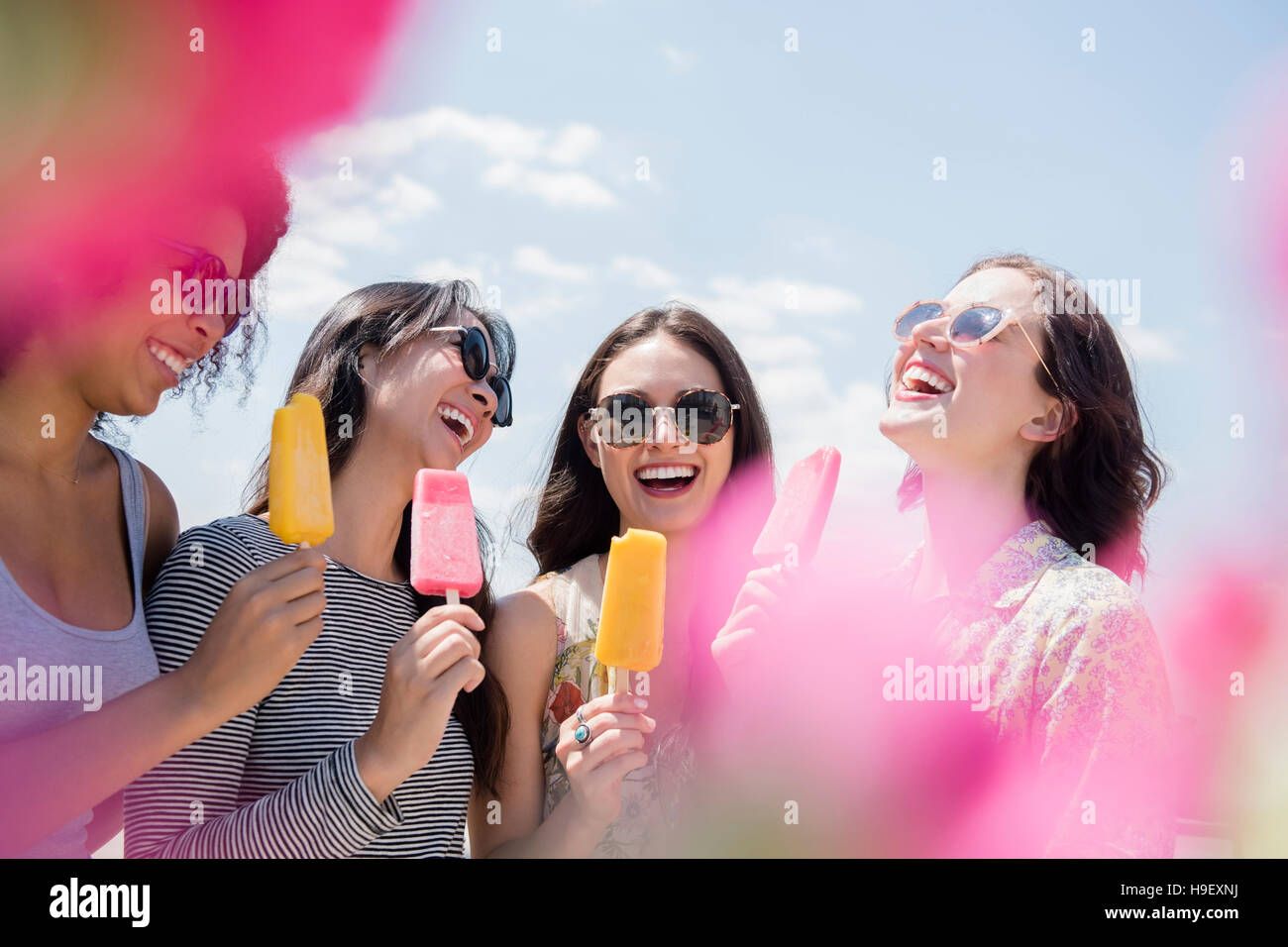 Laughing women eating flavored ice outdoors Stock Photo