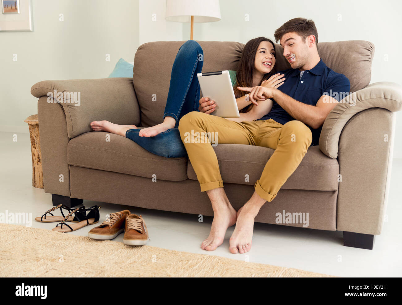 Парочка на белом диване крокус. Пара сидит на диване. Парень и девушка сидят на диване. Два человека сидят на диване. Два человека на диване.