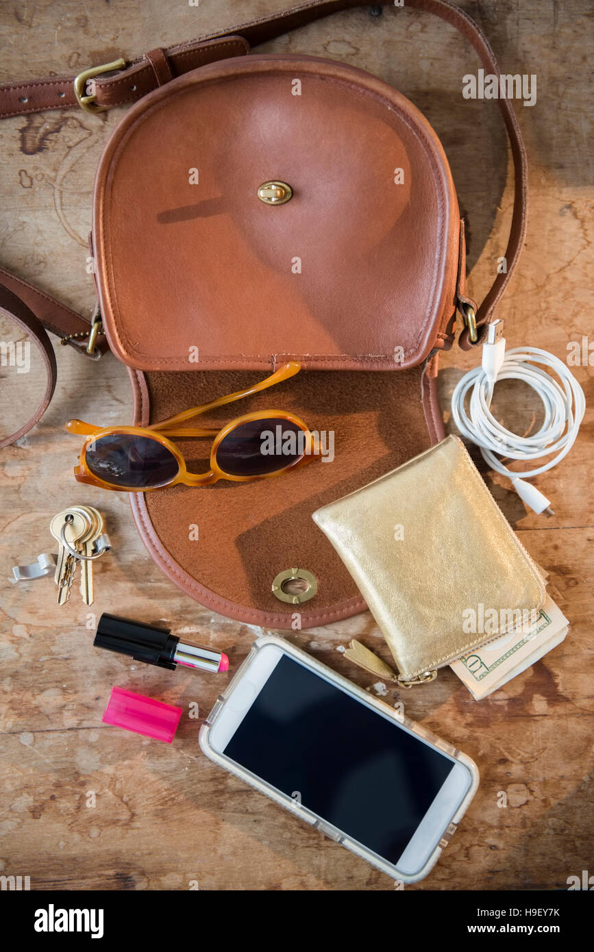 Purse with wall, cell phone, lipstick and sunglasses Stock Photo