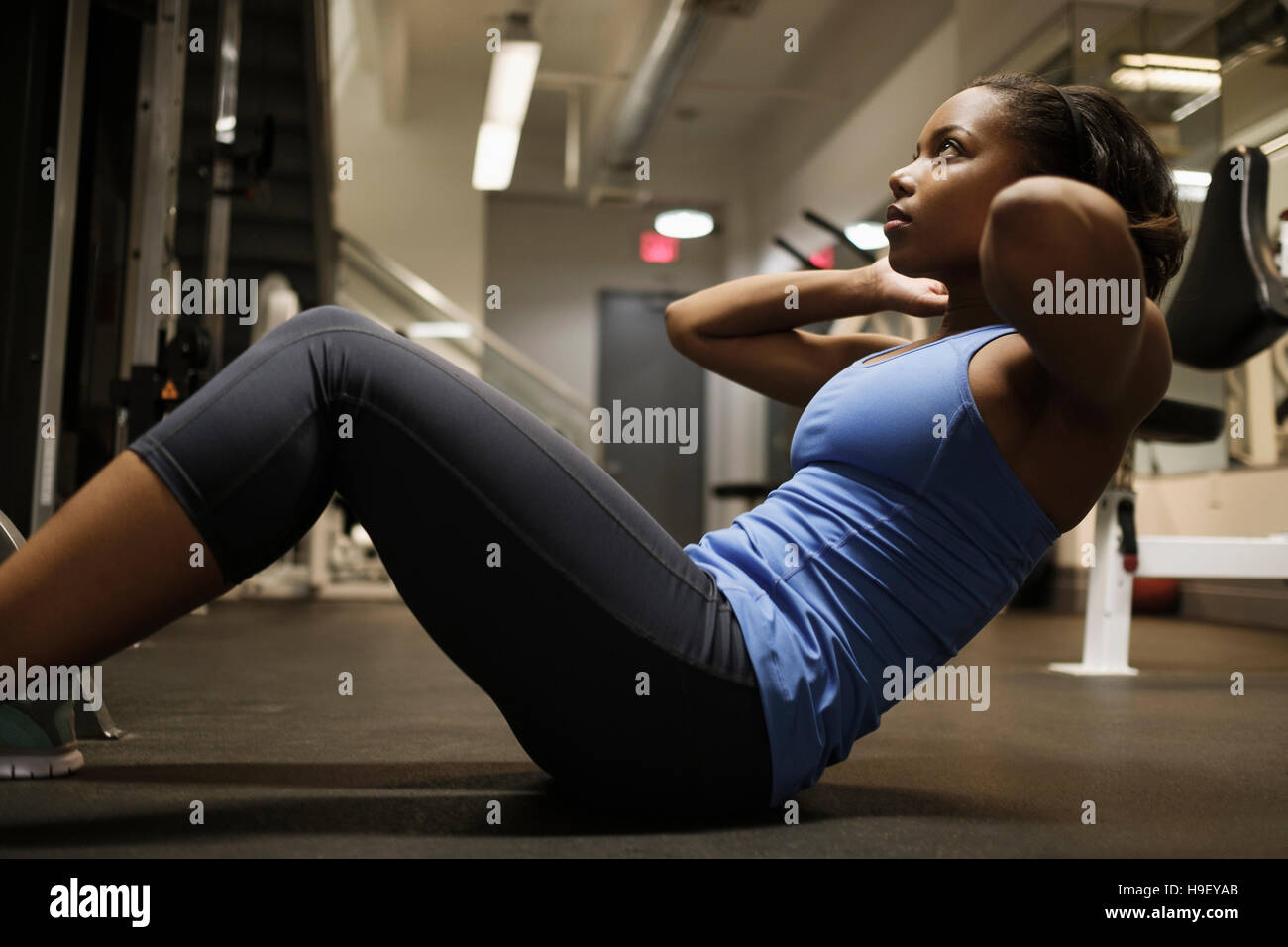 Mixed Race woman doing sit-up on floor at gymnasium Stock Photo - Alamy