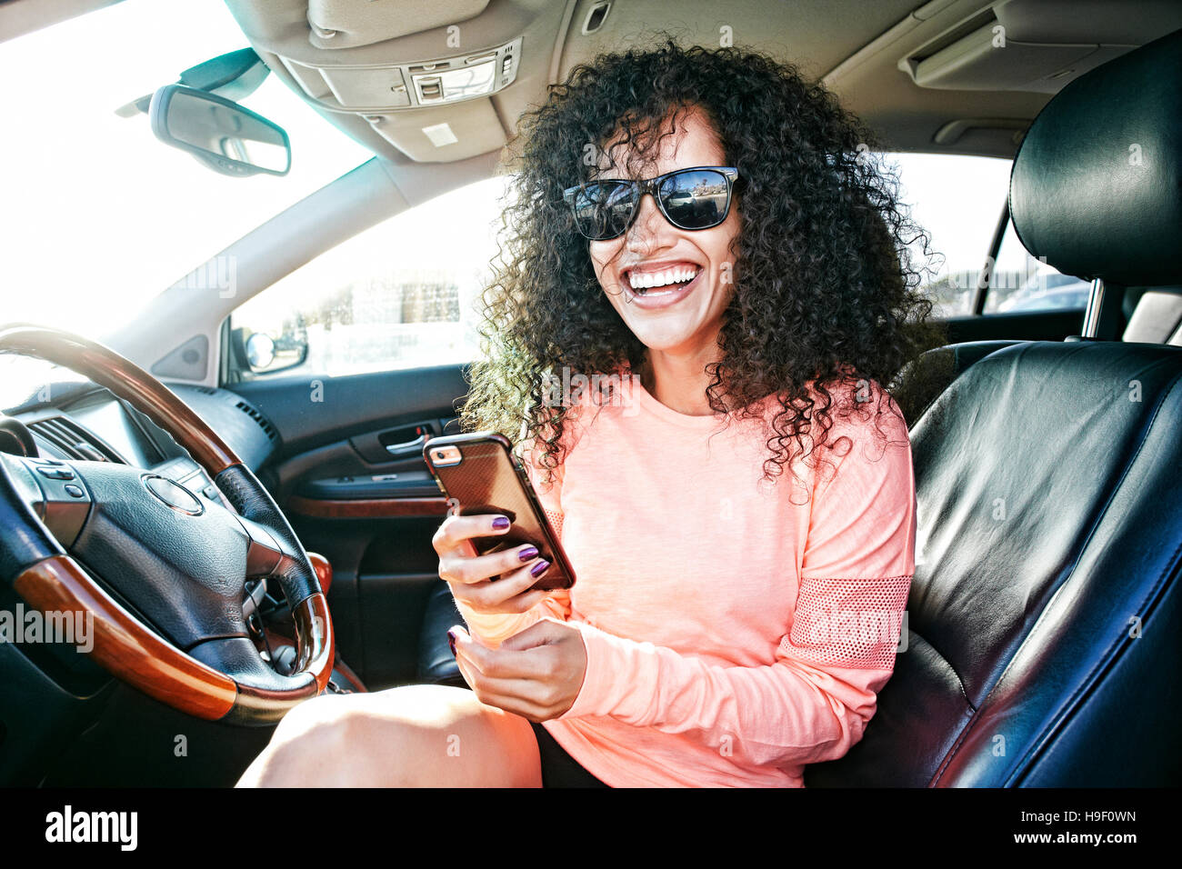 Laughing Hispanic woman in car holding texting on cell phone Stock ...
