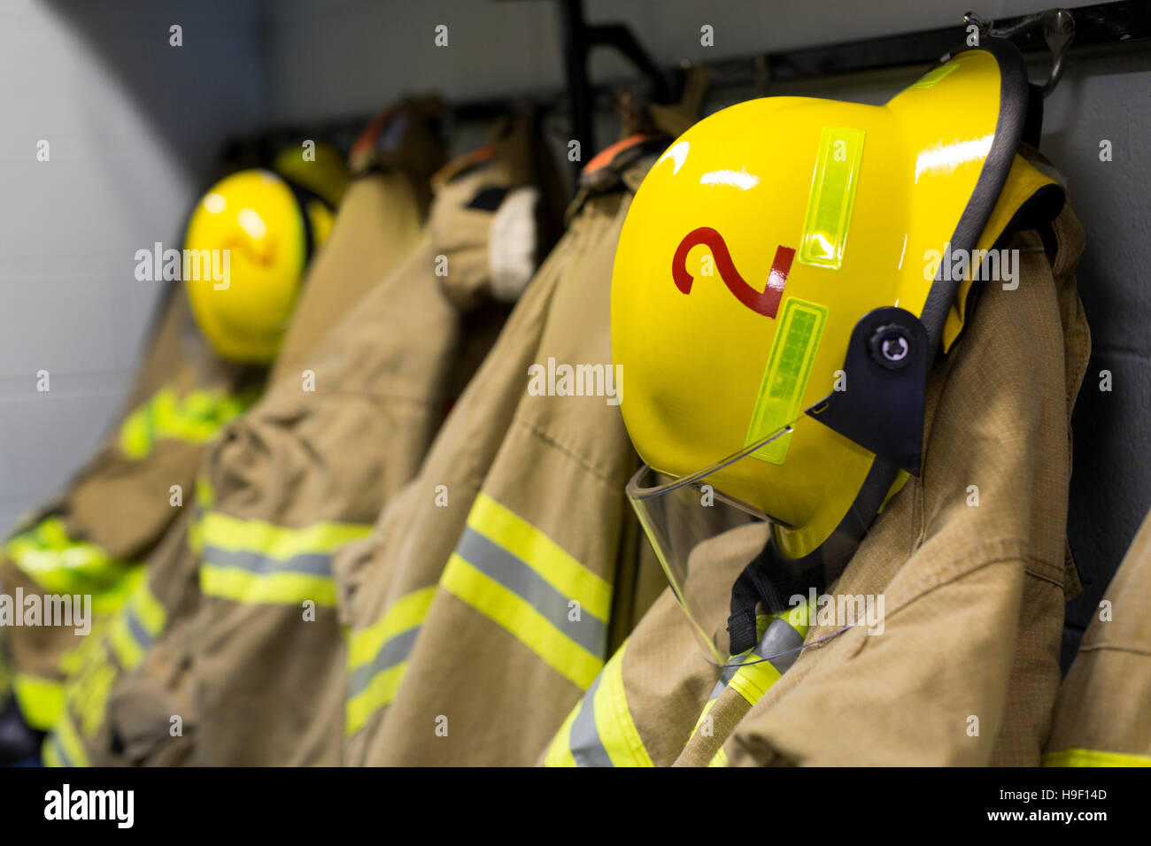 Coats and helmets of fire fighters hanging on hooks Stock Photo