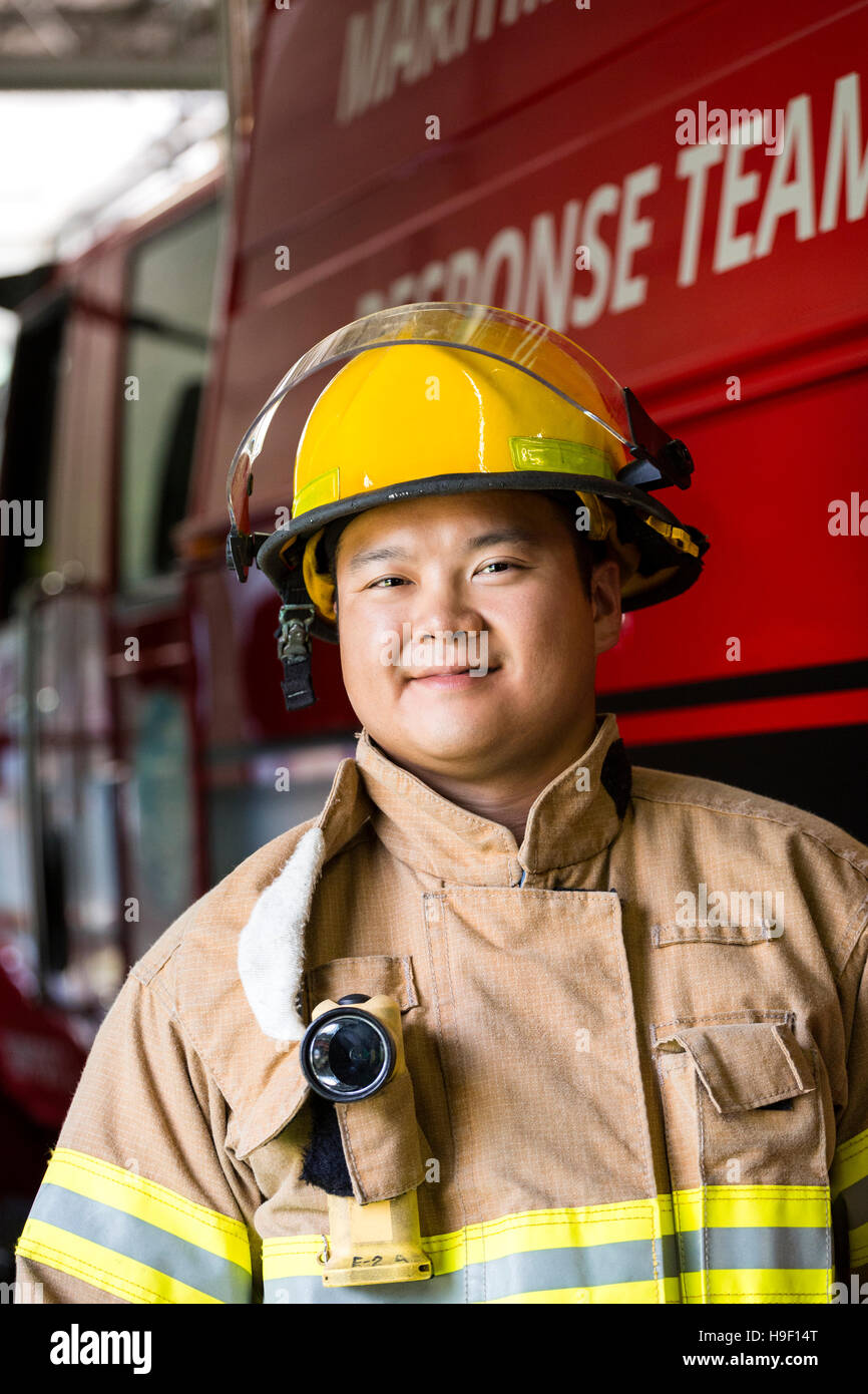 Smiling Chinese fireman standing near fire truck Stock Photo
