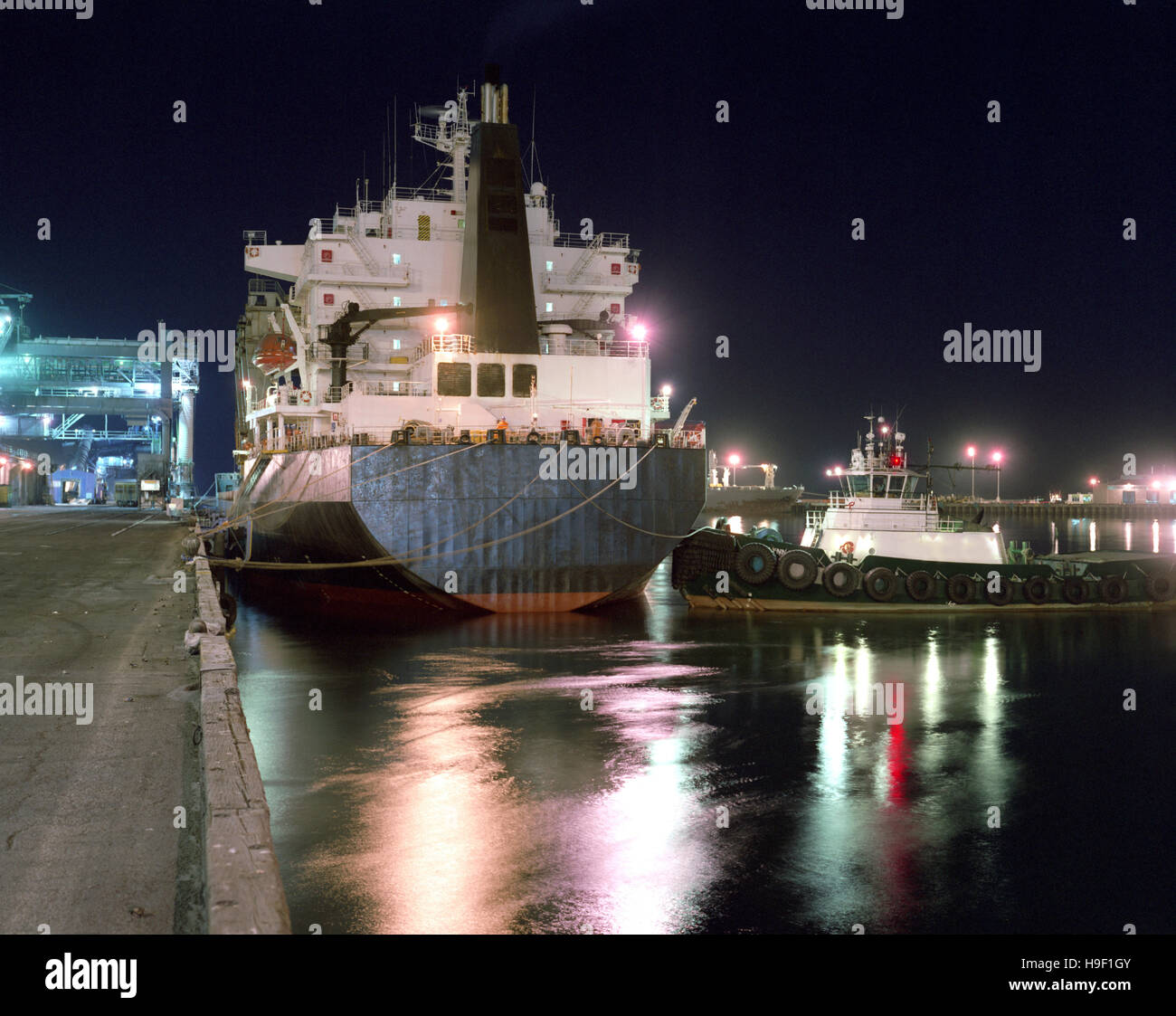 Tugboat and ship moored in harbor Stock Photo