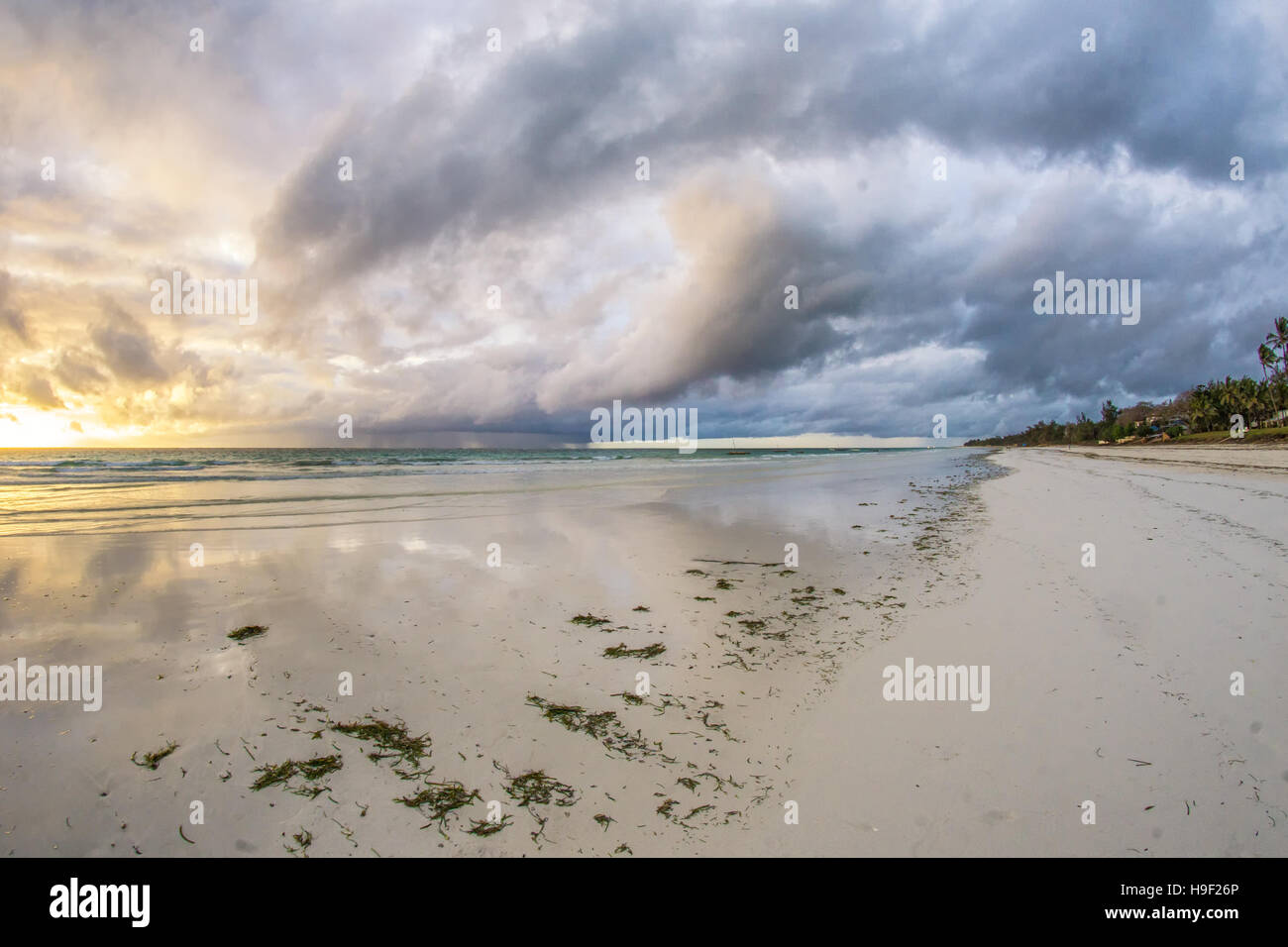 Beautiful sunrise behind the thunderous clouds over the white sand beaches of Diana Beach in Mombasa Kenya Stock Photo