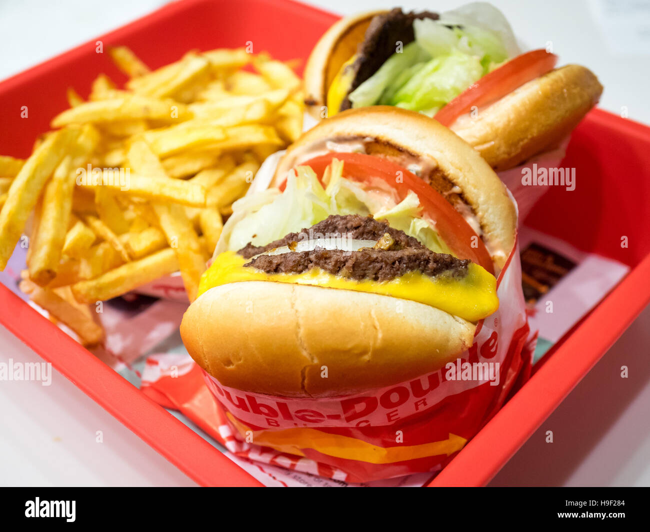 A 'double-double' cheeseburger (foreground), cheeseburger (background), and French fries from In-N-Out Burger in San Francisco. Stock Photo