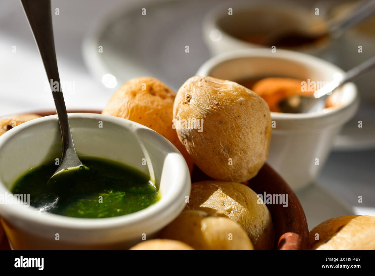 closeup of a plate with some papas arrugadas, typical Canarian wrinkly potatoes, and bowls with different mojo sauces, green mojo and red mojo or mojo Stock Photo