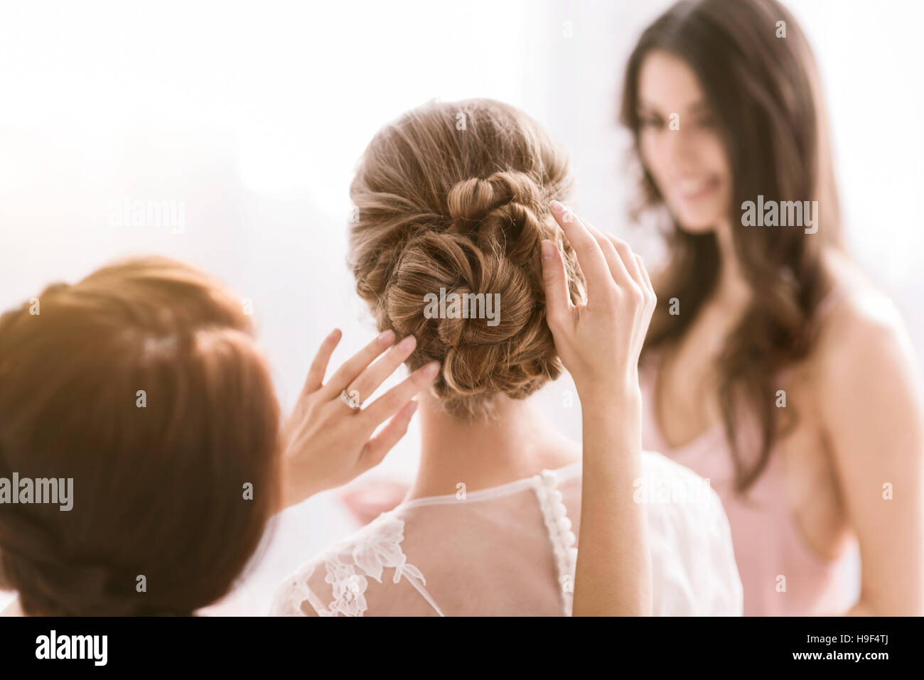 Pleasant bridesmaids helping the bride with her hairstyle Stock Photo