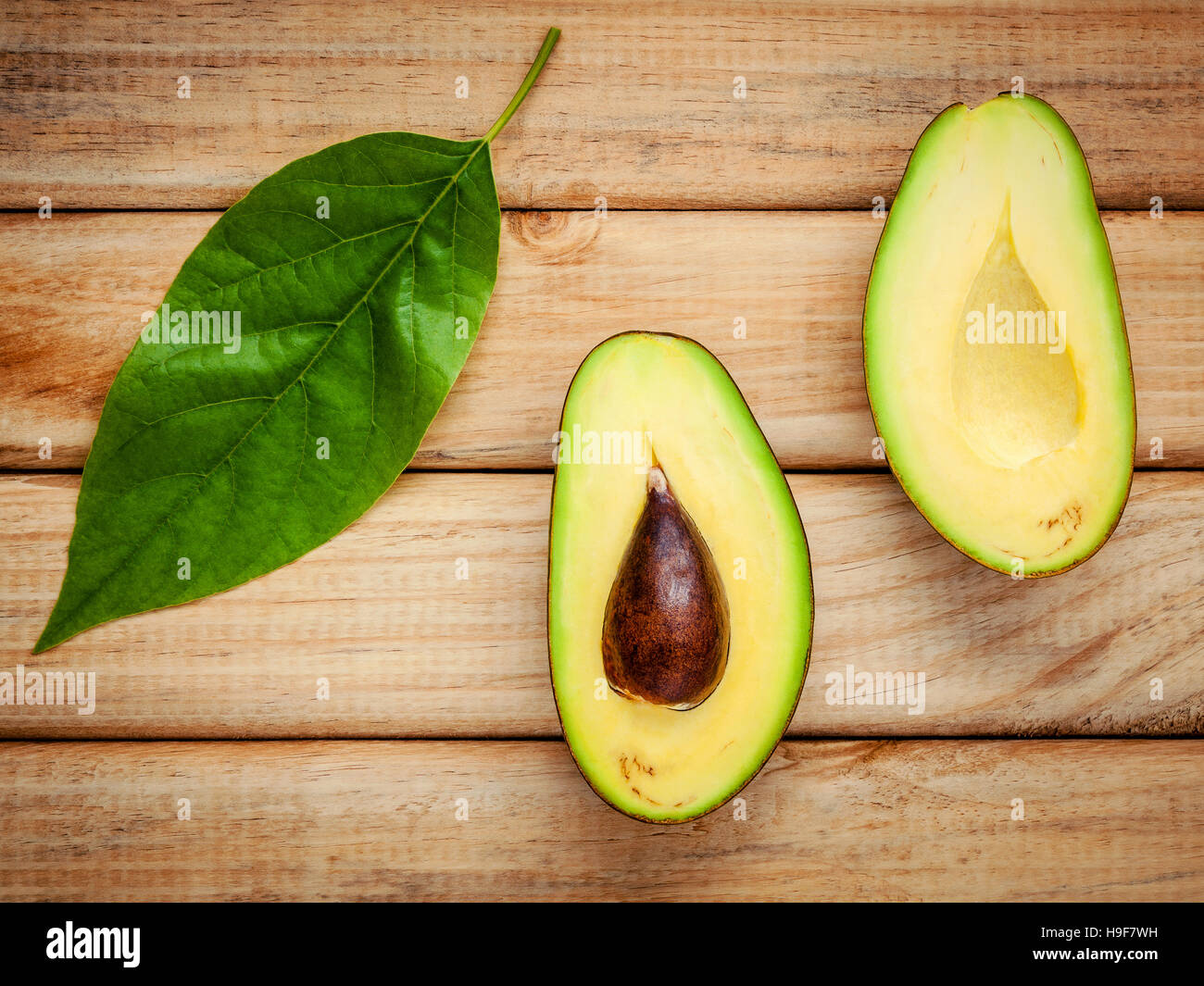Fresh avocado with avocado leaves on wooden background. Organic Stock Photo