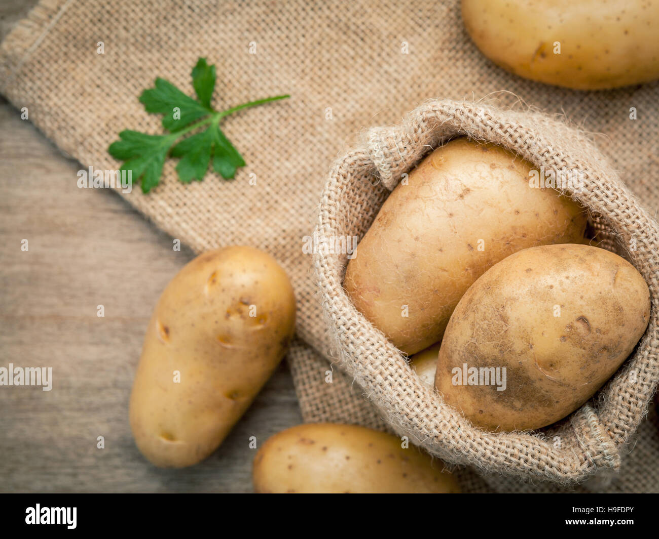 Closeup fresh organic potatoes in hemp sake bag with parsley on Stock Photo