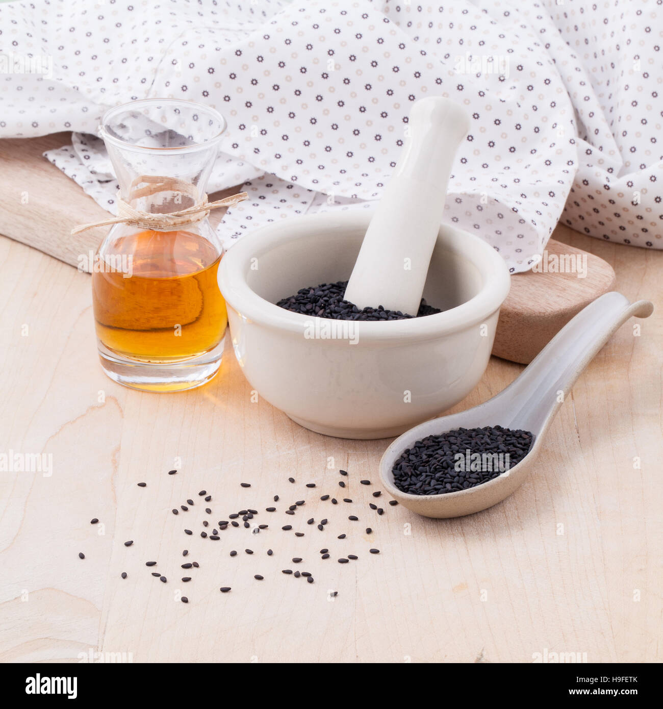 Black sesame oil and sesame seeds set up on wooden table Stock Photo
