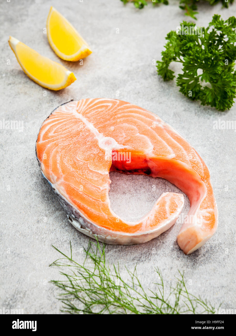 Fresh salmon fillet slice on dark stone background with herbs fe Stock Photo