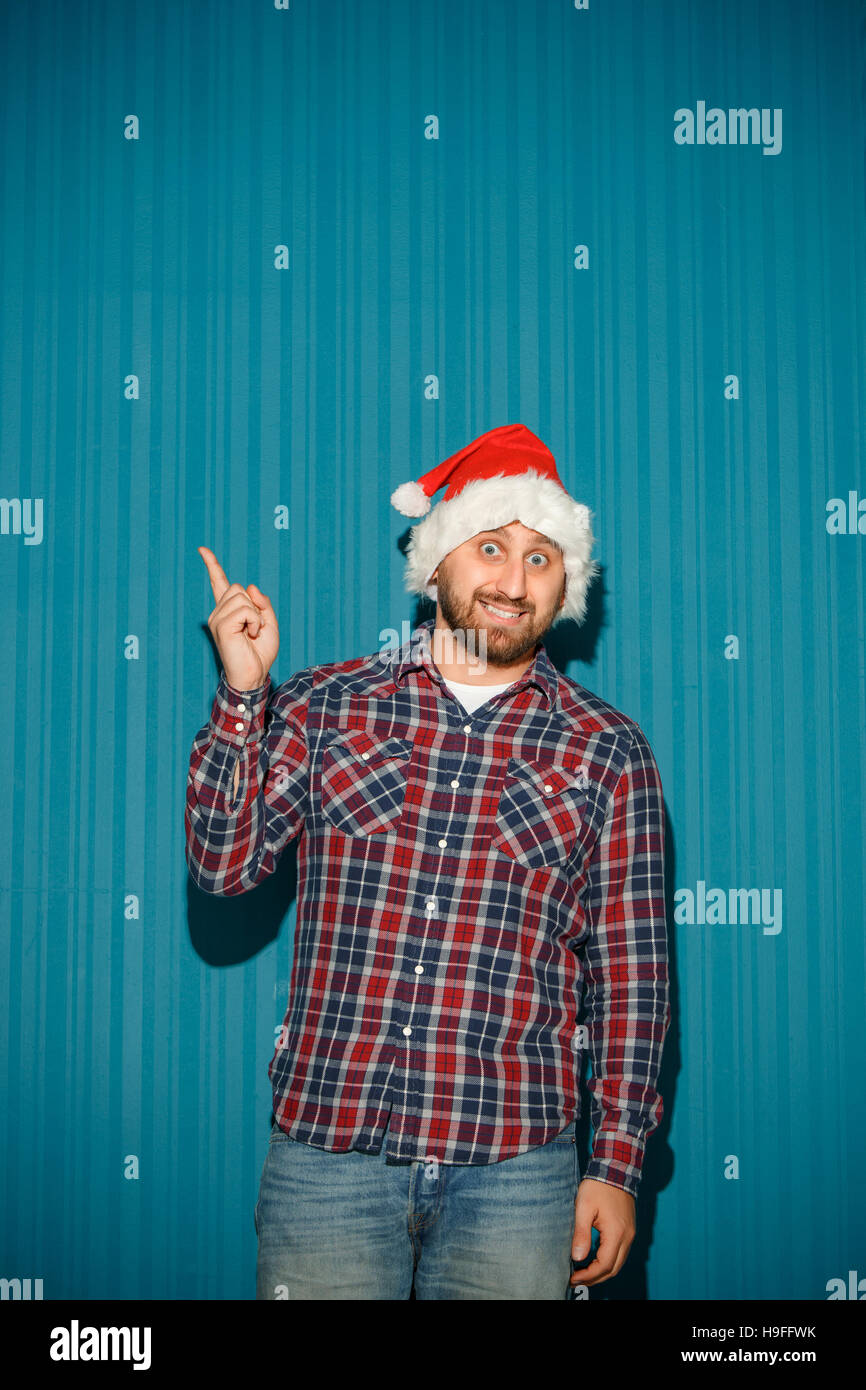 Smiling christmas man wearing a santa hat on the blue studio background ...