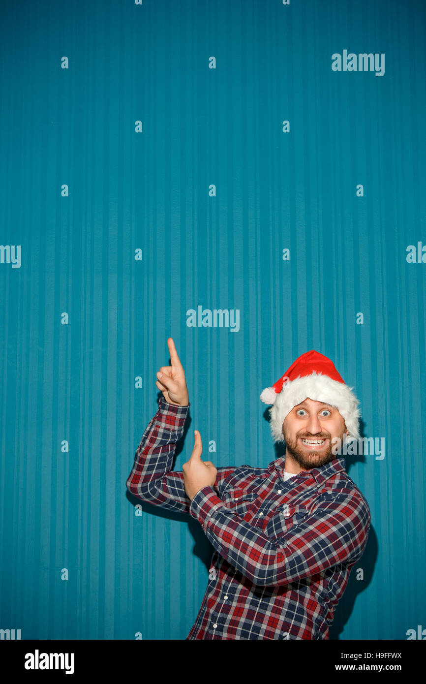 Smiling christmas man wearing a santa hat on the blue studio background ...