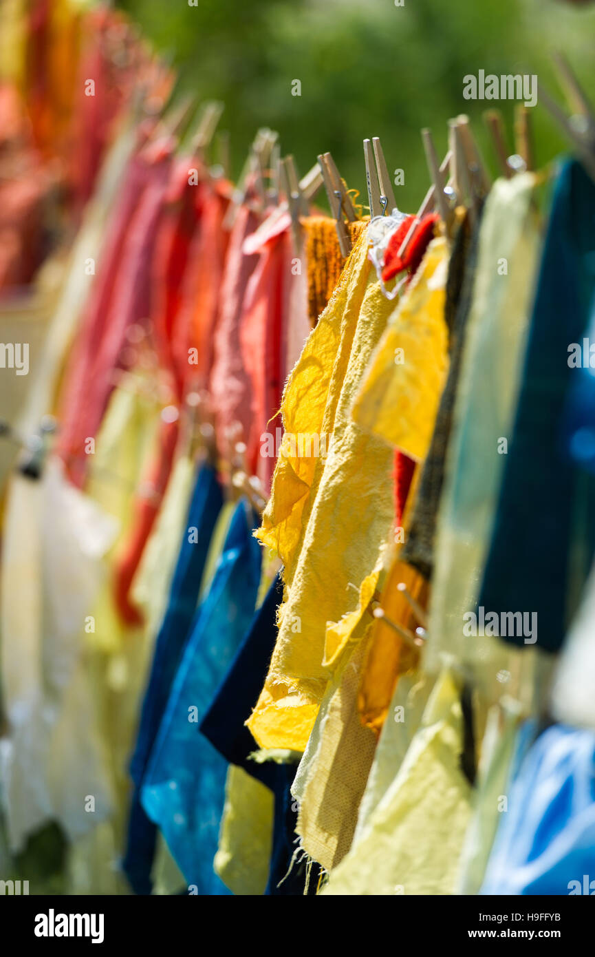 Colourful fabric dyed with natural dyes, hanging on a line outside to dry. Stock Photo