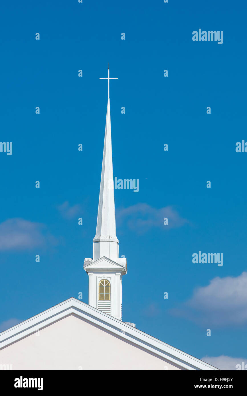 Tall white church steeple with cross on top against a blue sky in Punta Gorda Florida Stock Photo