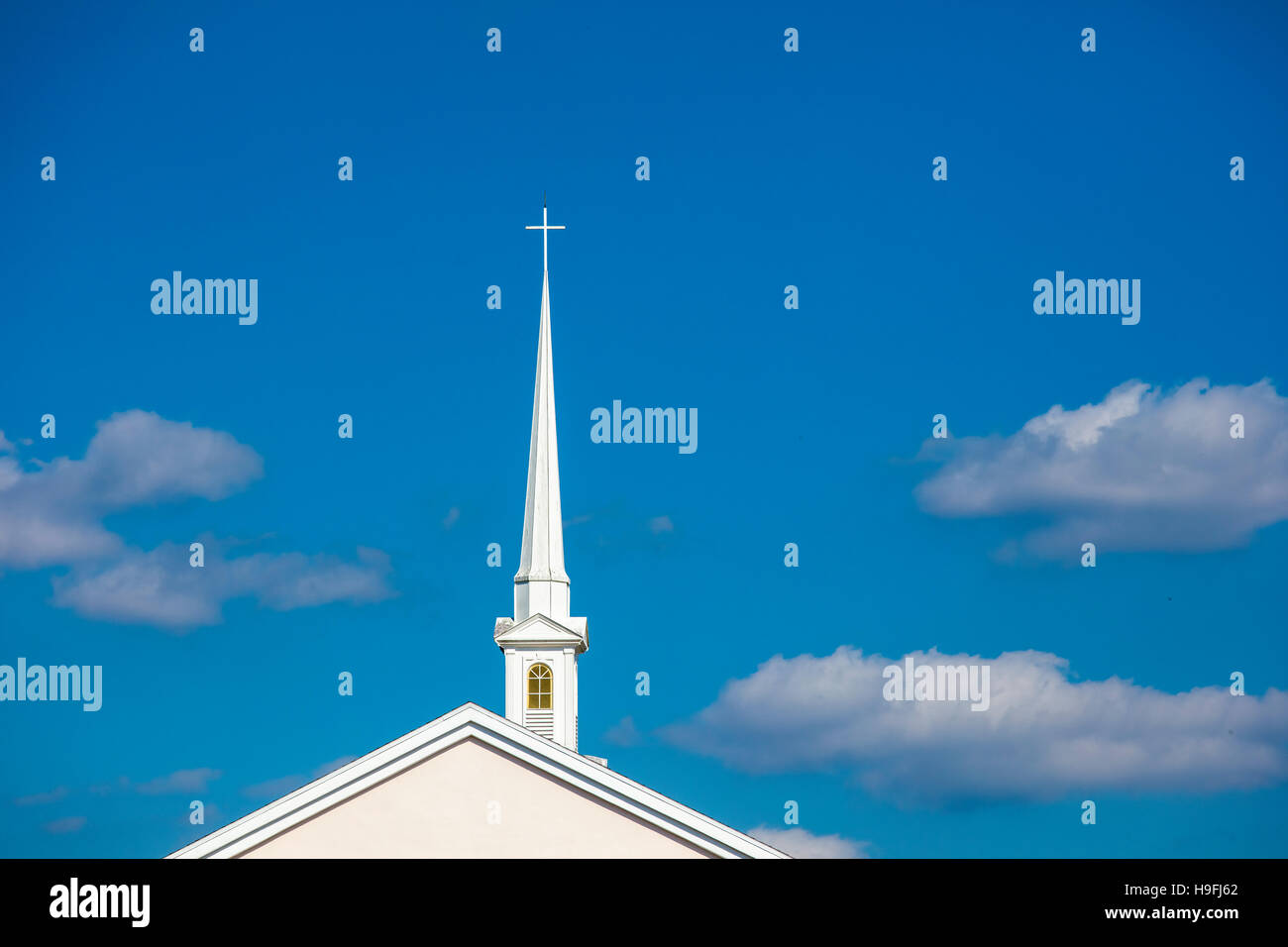 Tall white church steeple with cross on top against a blue sky in Punta Gorda Florida Stock Photo