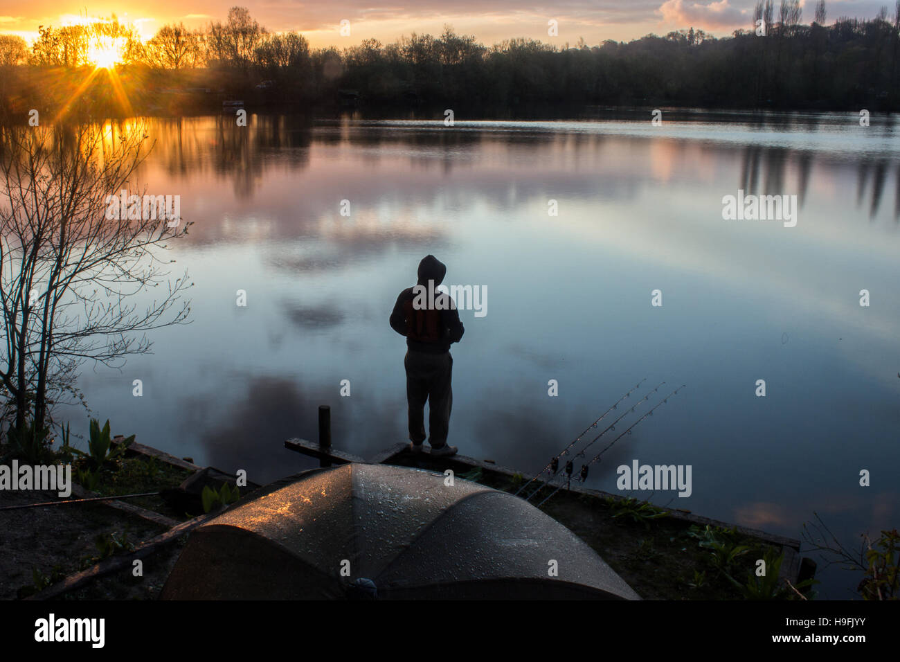 Sunrise with a Carp Angler overlooking Lake Stock Photo