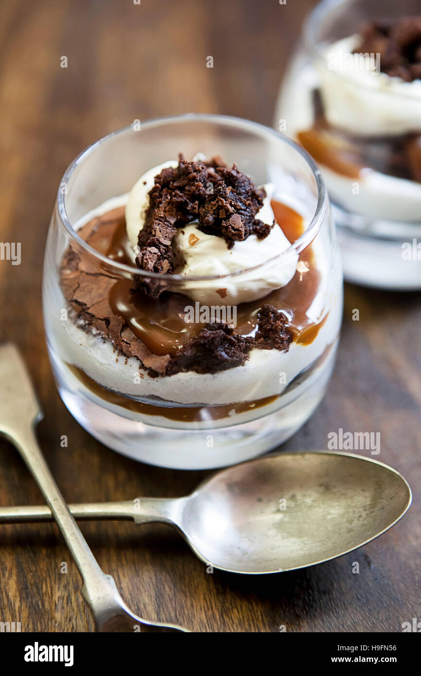 Pair of chocolate brownie caramel cheesecakes in glasses with old fashioned spoons Stock Photo