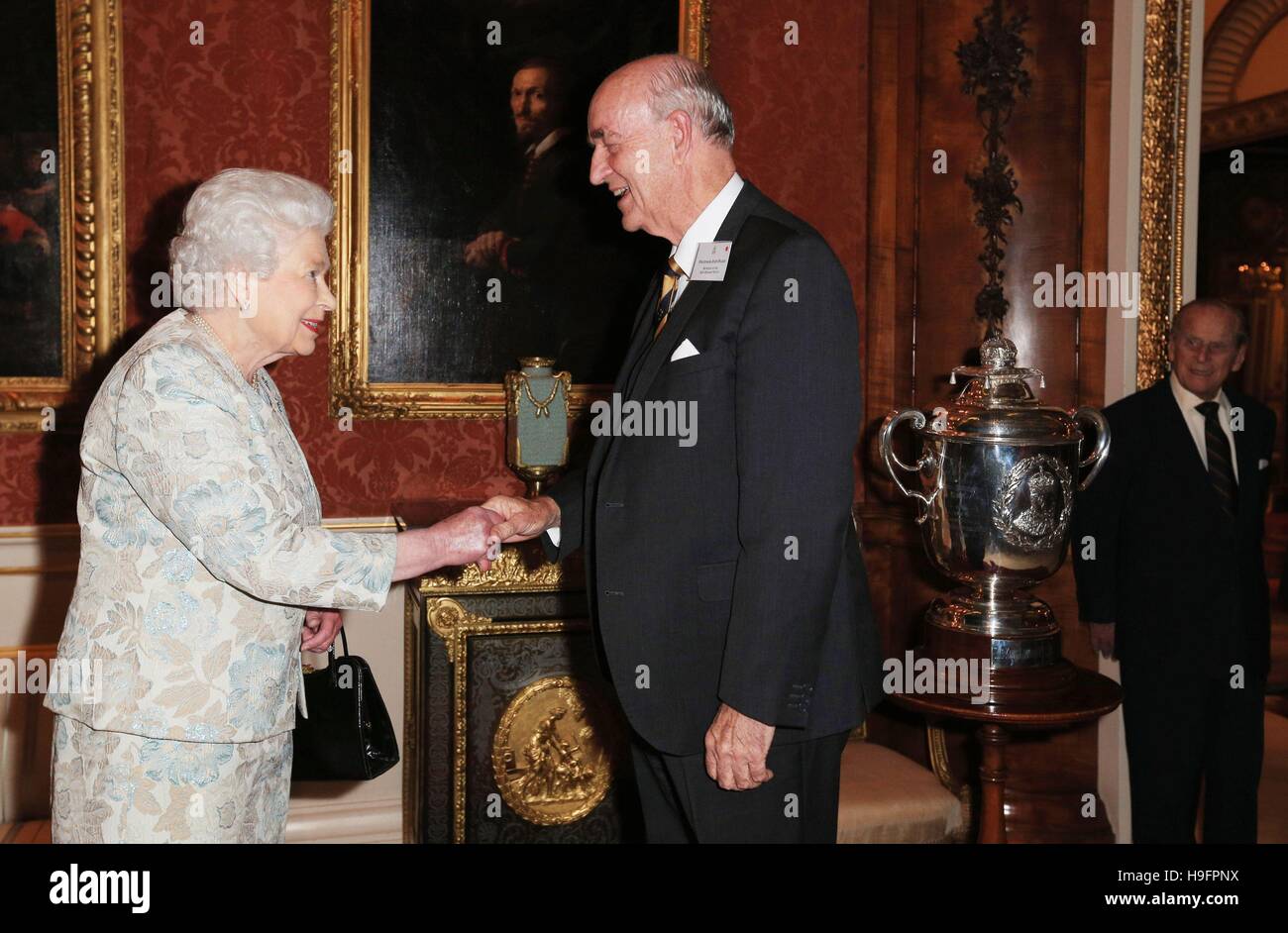 Queen Elizabeth II congratulates Professor John Pearn, from Australia for receiving the King Edward VII Cup (right) during a reception held for the Royal Life Saving Society at Buckingham Palace, London. Stock Photo