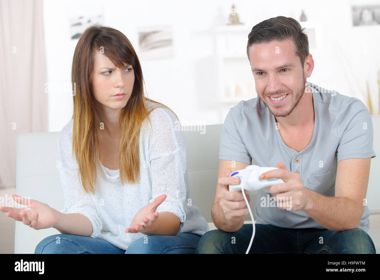 Man disappointed while playing video game with girlfriend at home stock  photo