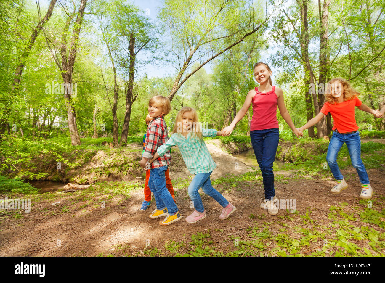 Happy kids walking in the park holding hands Stock Photo - Alamy