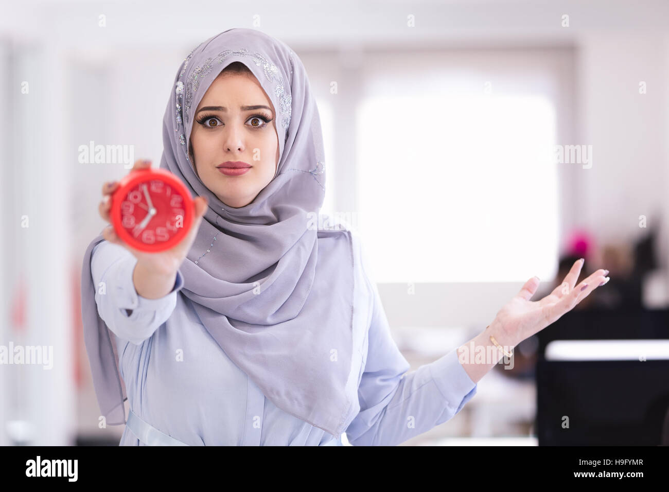 Arab Businesswoman with clock being late wearing hijab Stock Photo