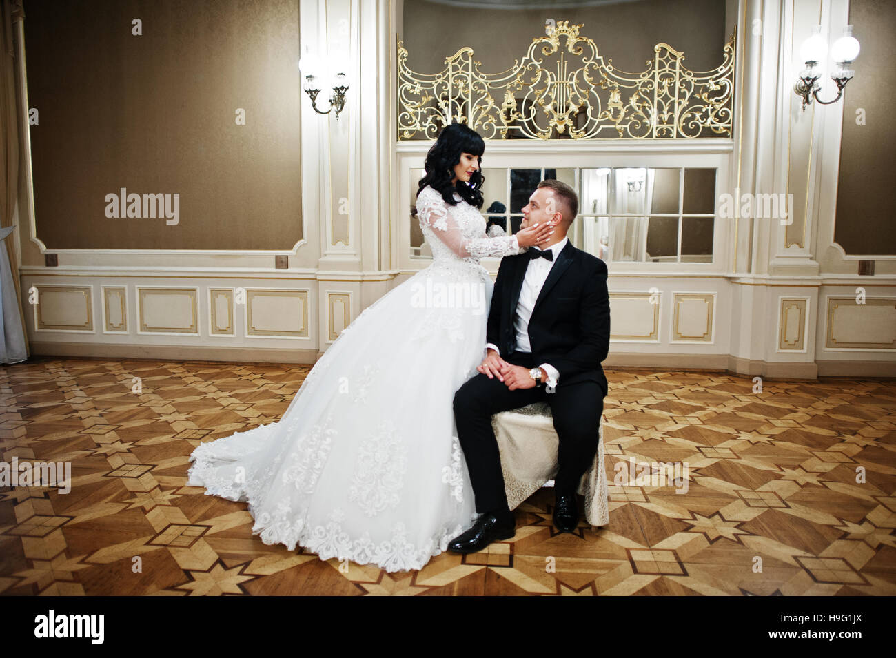 Magnificent wedding couple sitting on chair on royal room with