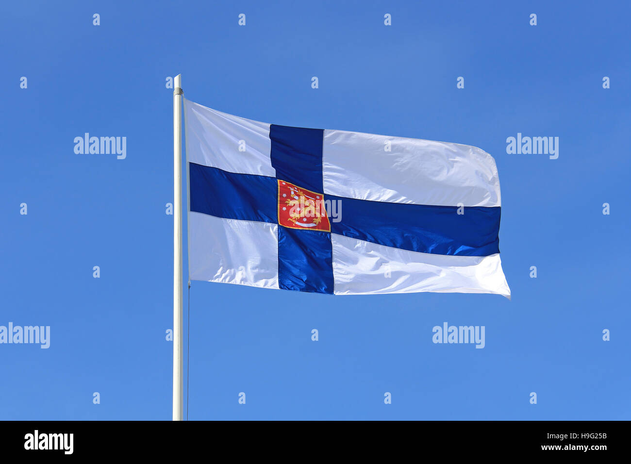 Finland State Flag with Finnish National Coat of Arms against blue sky. Stock Photo