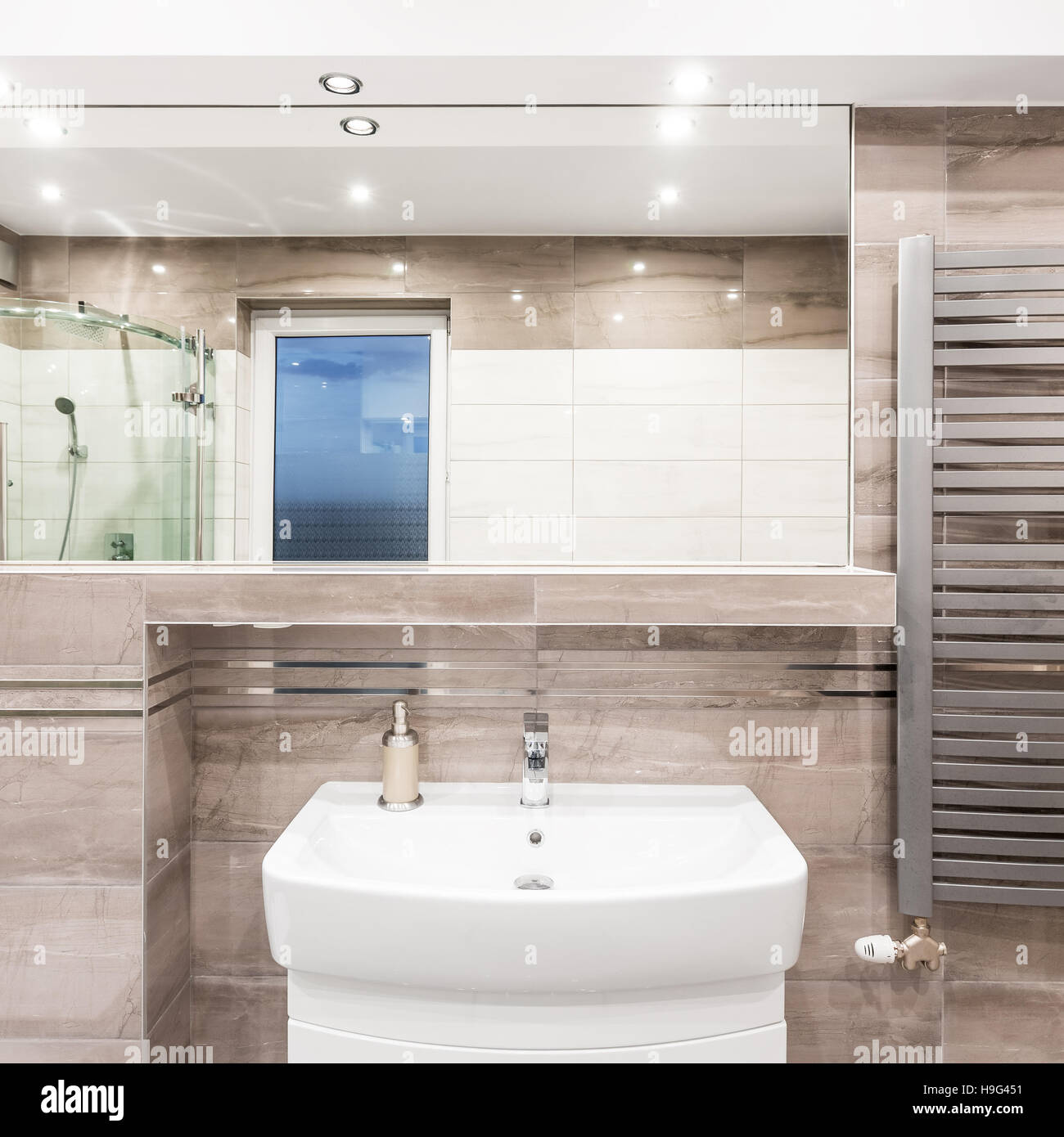 Beige bathroom with washbasin, mirror, shower and stylish radiator ...