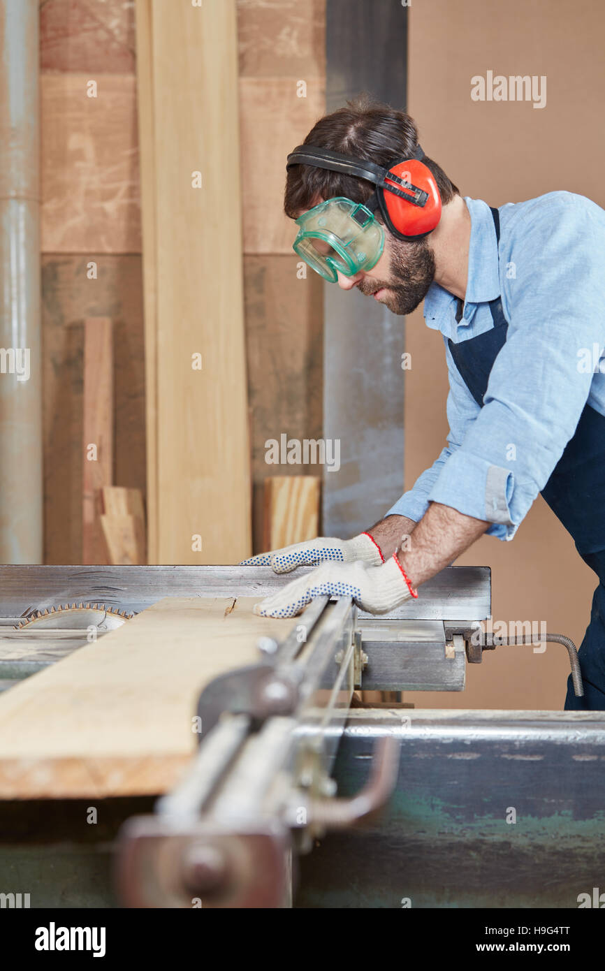 Artisan working with ear and eyes protection at carpentry workshop Stock Photo