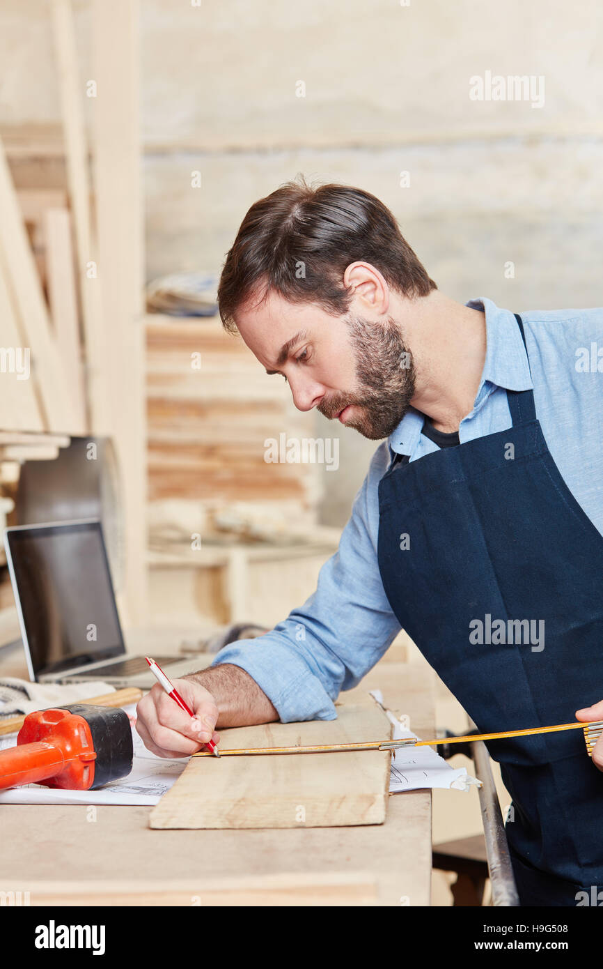 Carpenter measures wood with accuracy at workshop Stock Photo