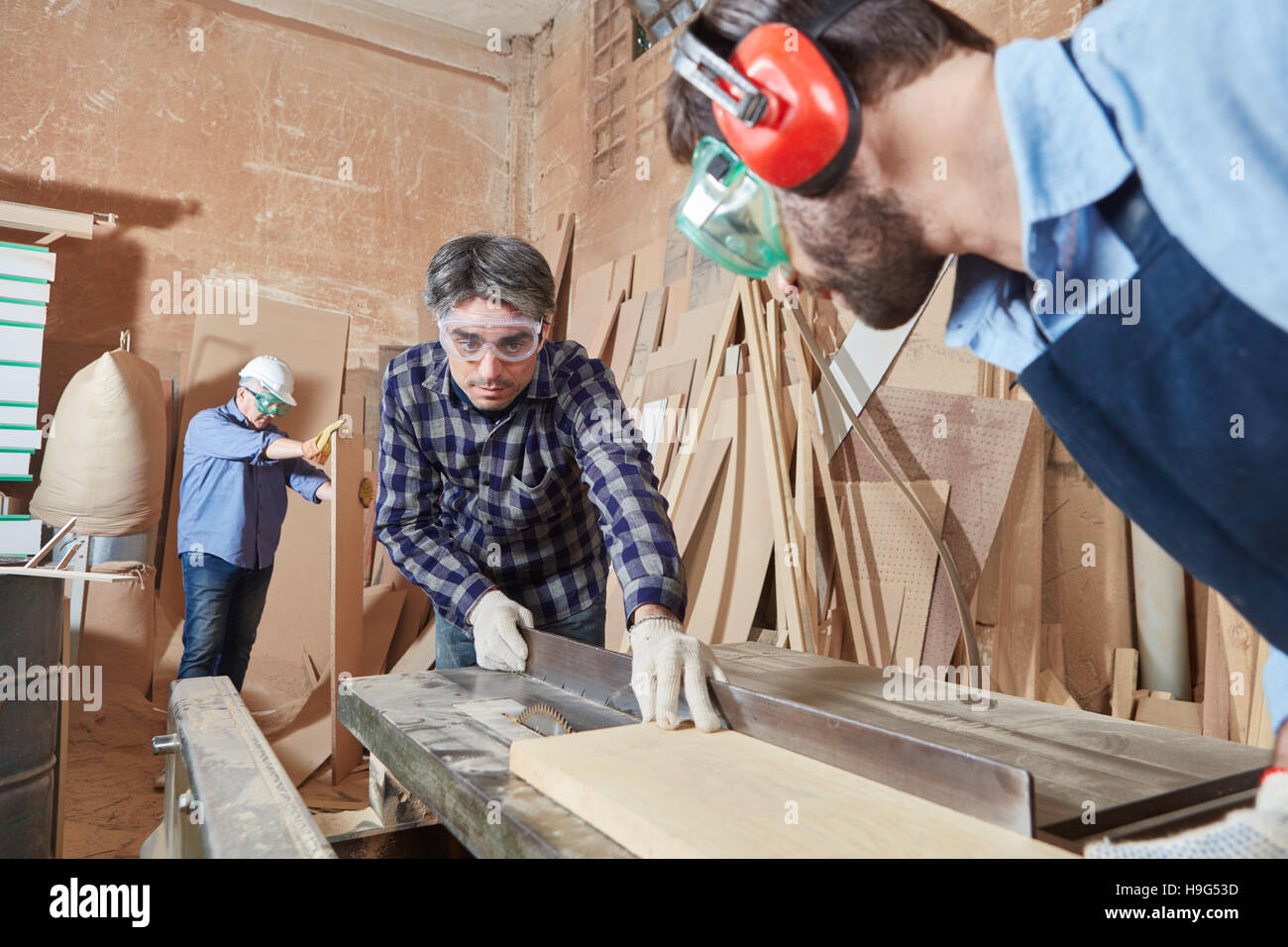 Two carpenters cutting wood with circular saw at workshop Stock Photo