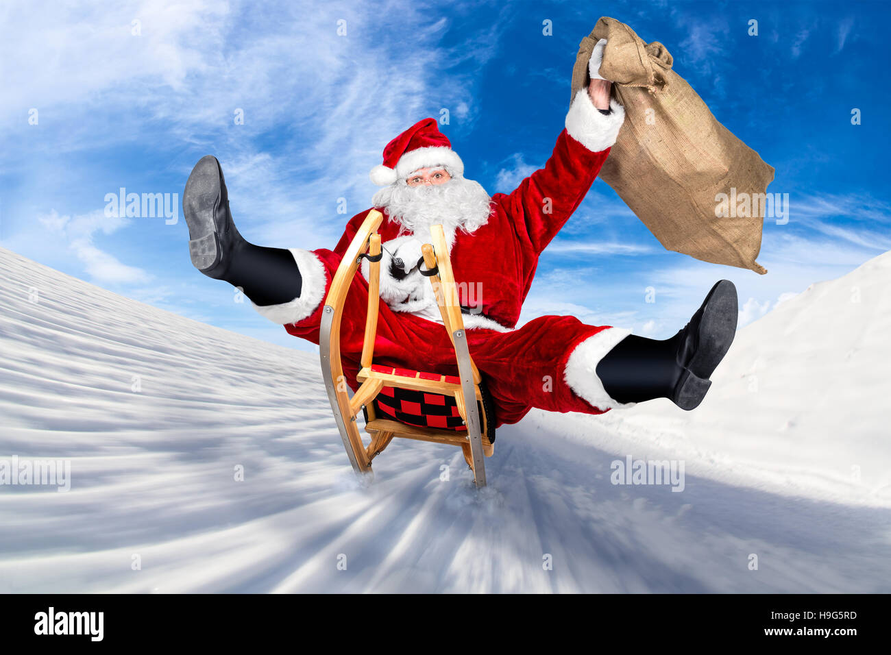 crazy santa claus on his sleigh hilarious fast funny crazy xmas christmas gift present delivery blue sky background Stock Photo