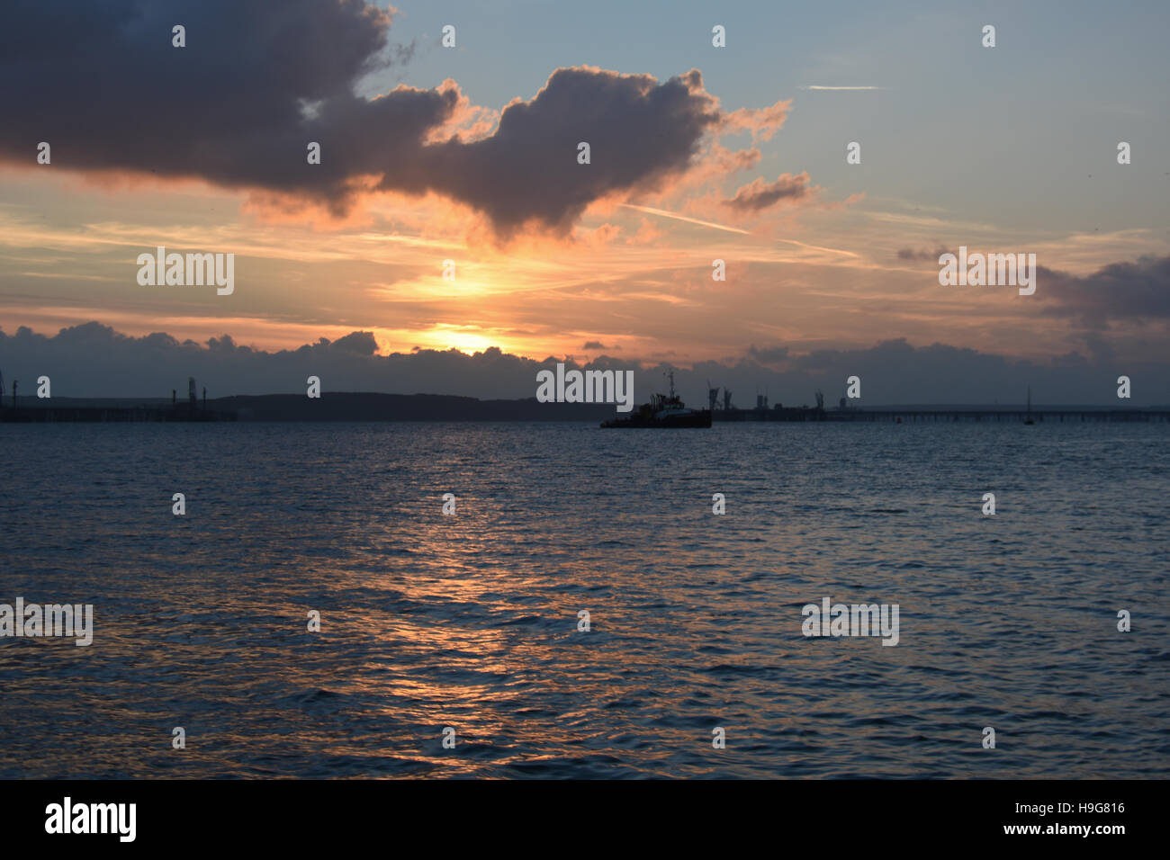 Tug boat waiting in calm sea at sunset  to enter Milford Haven dock Stock Photo