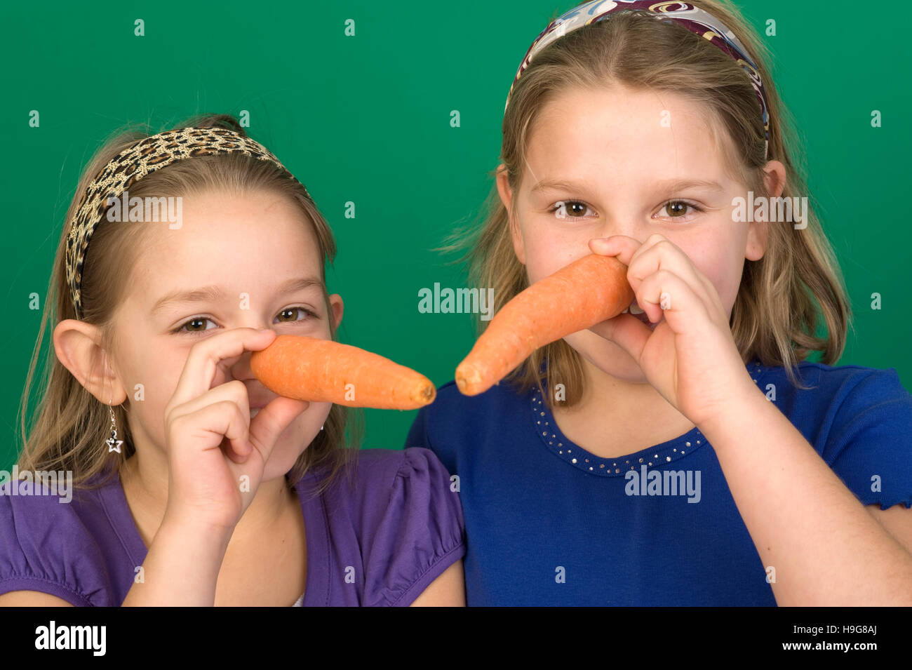 Girls holding carrots to their noses Stock Photo