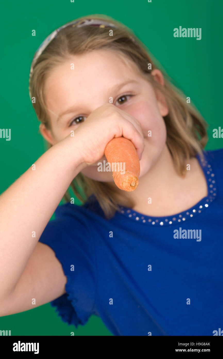 Girl holding a carrot to her nose Stock Photo