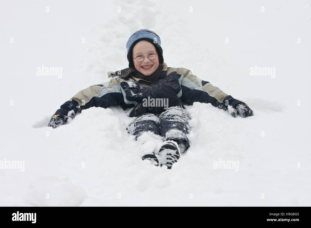 Seven-year-old boy sitting in the snow Stock Photo