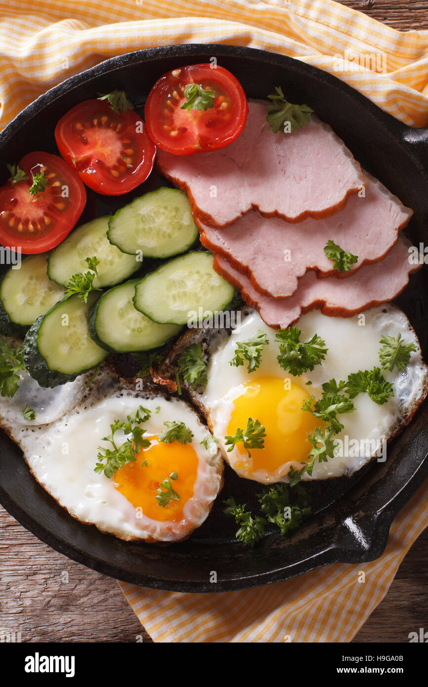 Hot breakfast: fried eggs with ham and fresh vegetables in a pan on the