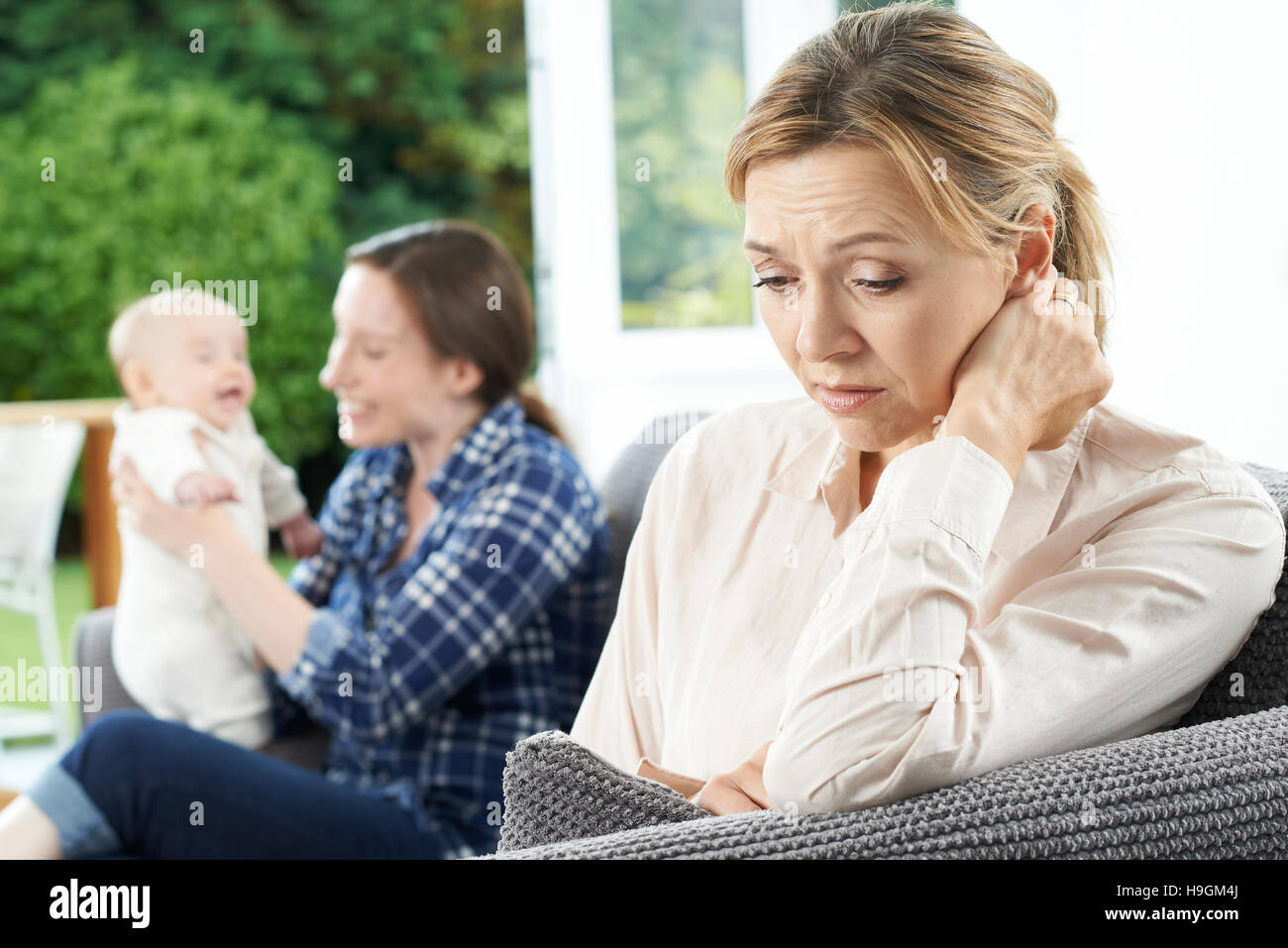 Sad Mature Woman Jealous Of Mother With Young Baby Stock Photo