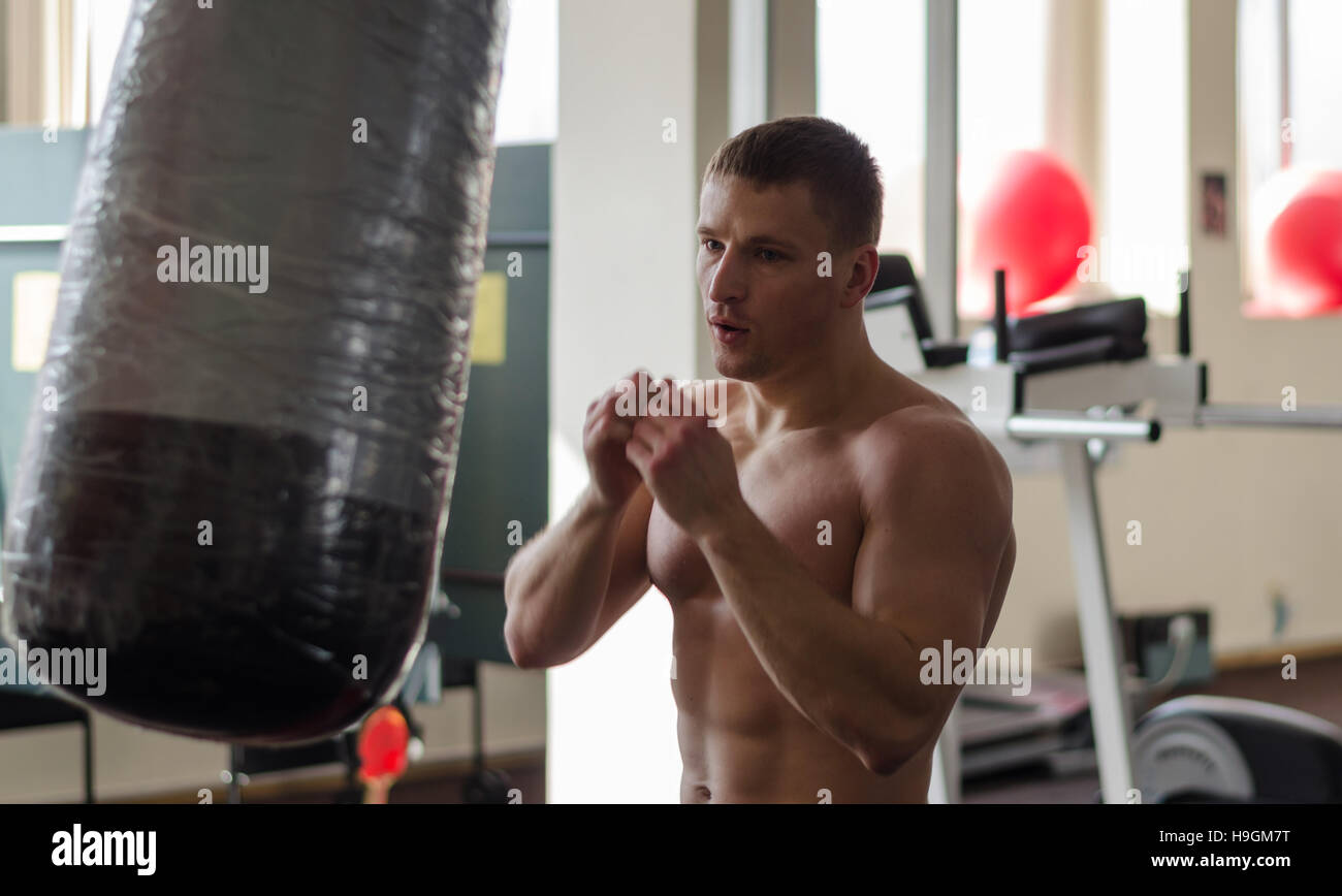 Young athlete in motion with blurred hands on training with a boxing bag gym Stock Photo