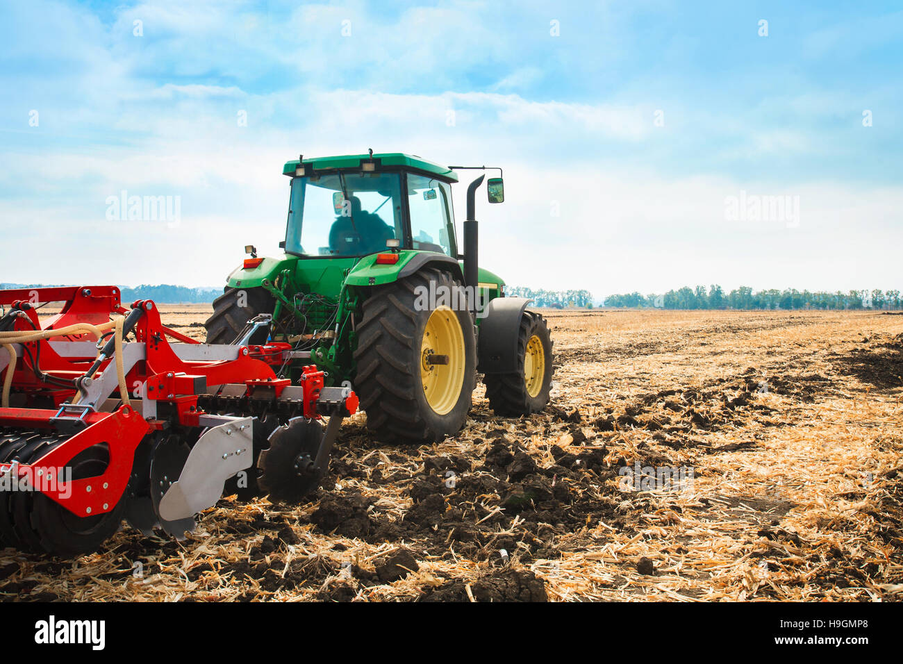 Tractor with a harrow in the field on a sunny day. The concept of work ...