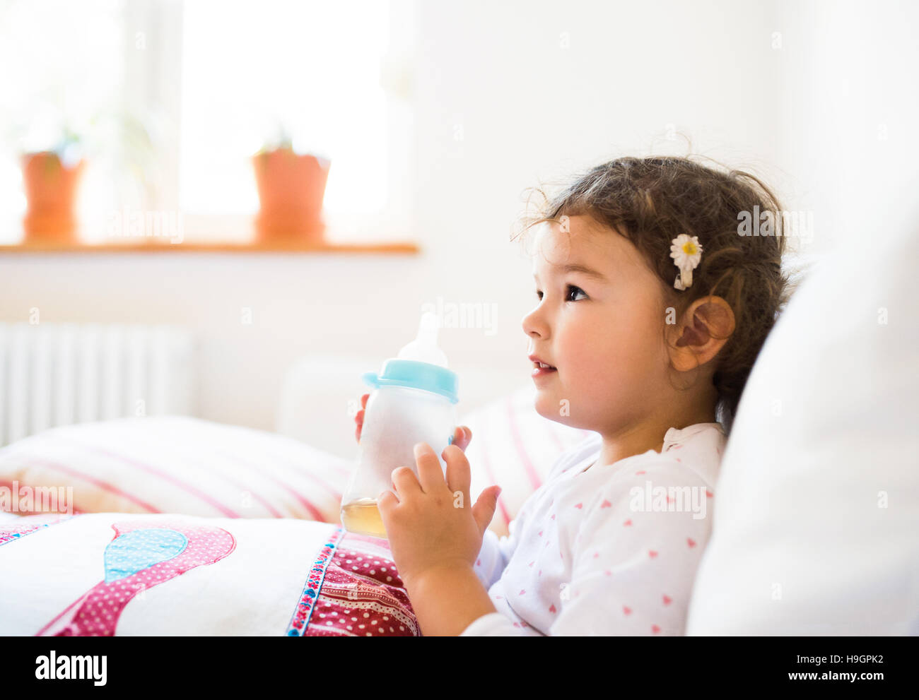 Cute little girl sitting on a couch in living room Stock Photo - Alamy